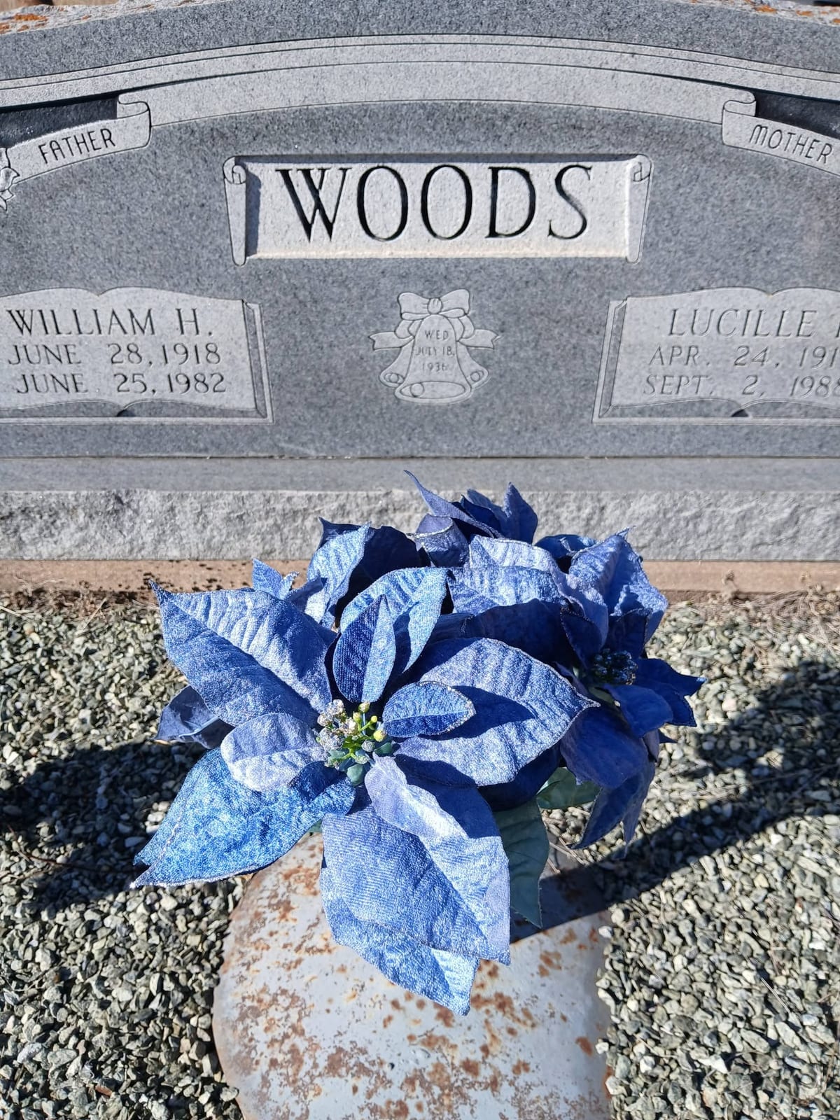 The Woods family headstone, William H. (1918–1982) and Lucille, with blue poinsettias in the vase before it.